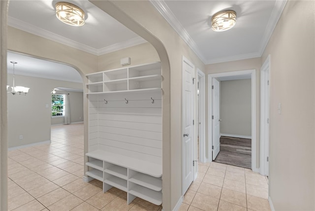 mudroom with a chandelier, light tile patterned floors, and crown molding