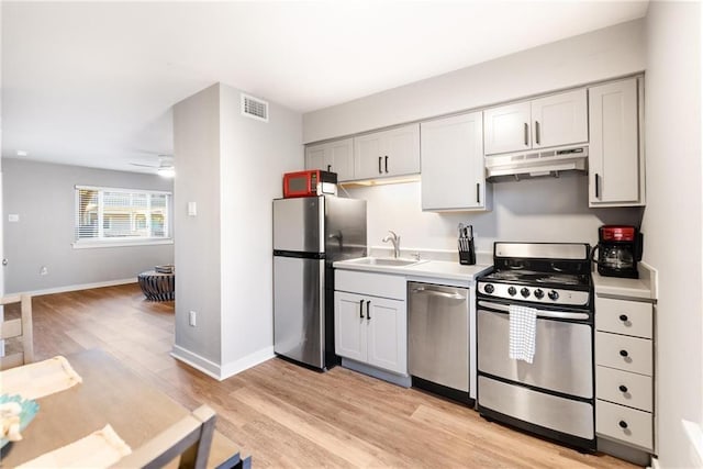 622 Beach Access Road 1a 116, Port Aransas, TX 78373 - kitchen with appliances with stainless steel finishes, under cabinet range hood, a sink, light wood finished floors, and baseboards