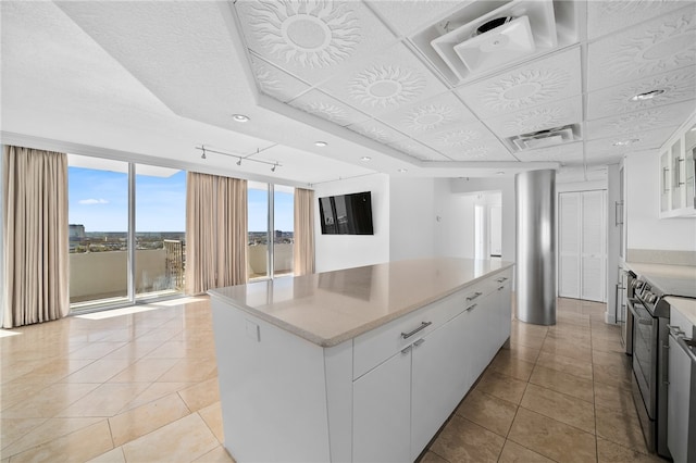 kitchen featuring white cabinetry, light tile patterned floors, a raised ceiling, a center island, and electric range