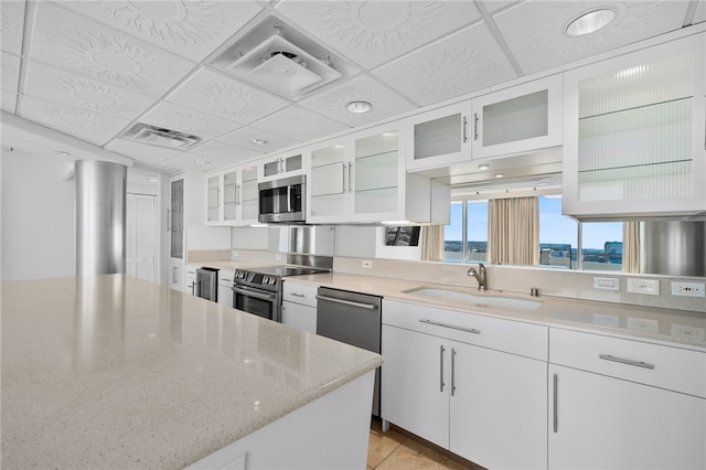 kitchen with white cabinetry, stainless steel appliances, sink, and a drop ceiling