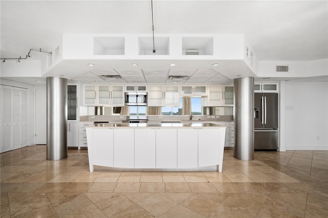 kitchen with stainless steel appliances, white cabinets, sink, light tile patterned floors, and a kitchen island