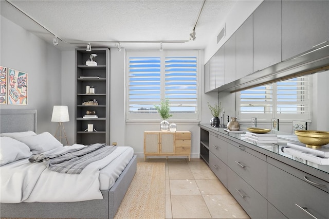 bedroom featuring a textured ceiling, light tile patterned floors, and rail lighting