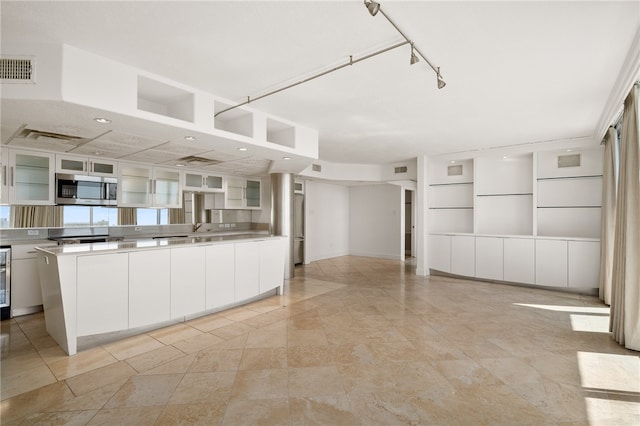 kitchen with stainless steel counters, white cabinetry, sink, and a kitchen island