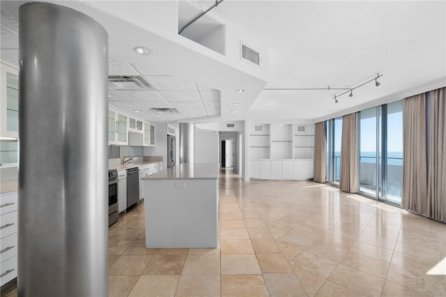 kitchen featuring stainless steel appliances, white cabinetry, sink, a water view, and light tile patterned floors