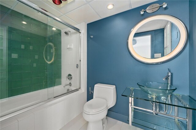 full bathroom featuring toilet, bath / shower combo with glass door, sink, and tile patterned floors