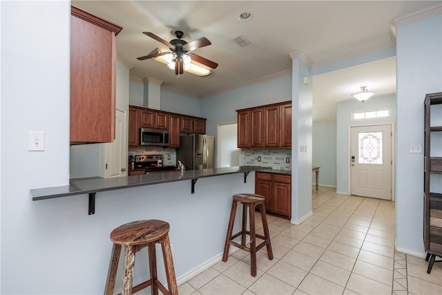 kitchen with stainless steel appliances, a kitchen breakfast bar, kitchen peninsula, and tasteful backsplash