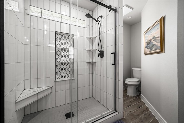 full bathroom featuring wood tiled floor, baseboards, a shower stall, and toilet