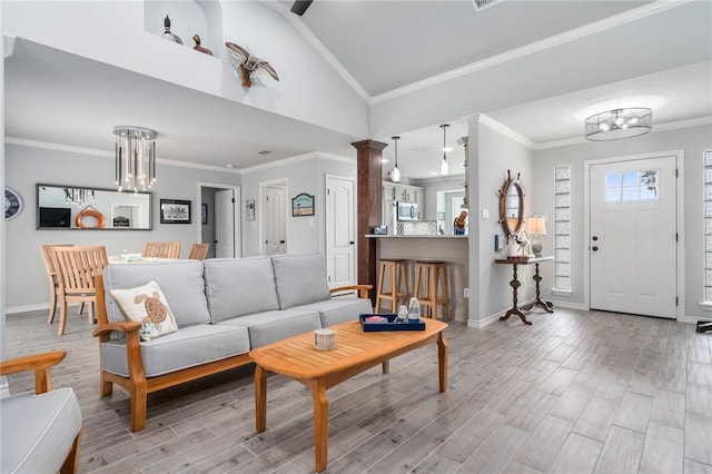 living area featuring an inviting chandelier, baseboards, vaulted ceiling, and light wood-style flooring
