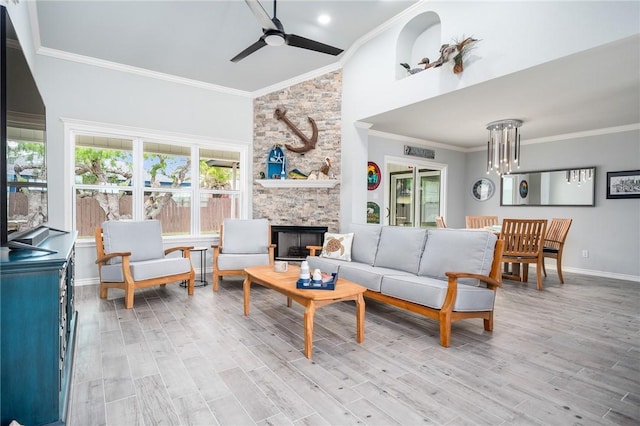 living room featuring baseboards, a ceiling fan, a fireplace, and ornamental molding