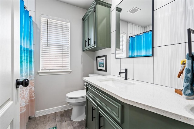 bathroom with vanity, toilet, baseboards, wood finished floors, and visible vents