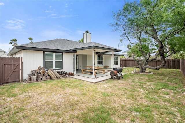 rear view of property with a chimney, a fenced backyard, a yard, a patio, and a shingled roof