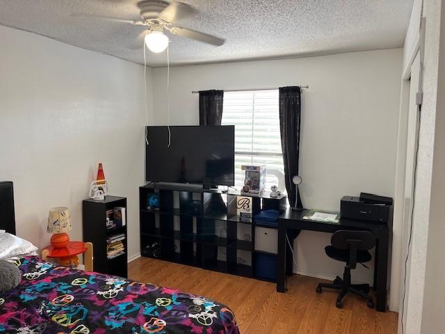 bedroom featuring hardwood / wood-style flooring, ceiling fan, and a textured ceiling