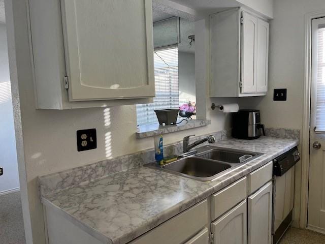 kitchen featuring white cabinets, dishwashing machine, and sink