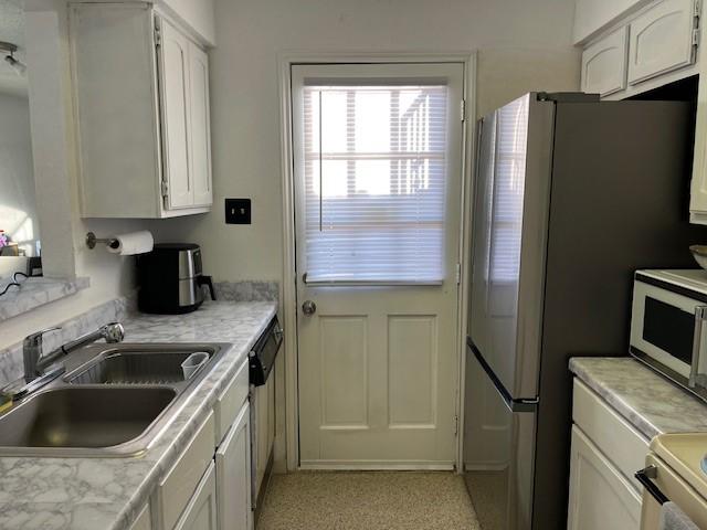 kitchen with white cabinetry, stainless steel dishwasher, and sink