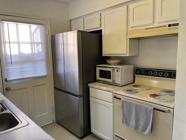 kitchen featuring white appliances, white cabinetry, and sink