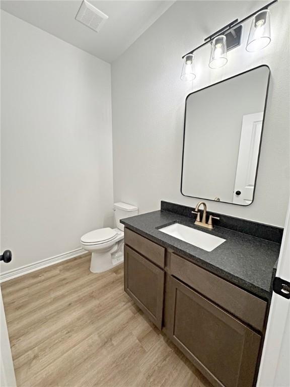 9505 Spanish Oak Dr, Corpus Christi, TX 78410 - half bathroom with wood finished floors, toilet, vanity, and baseboards