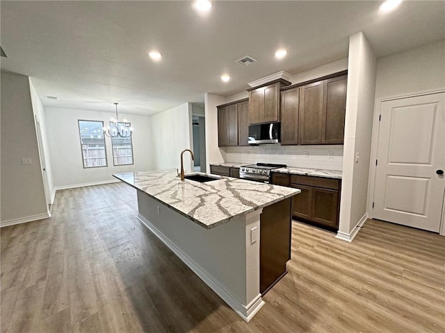 kitchen with sink, stainless steel appliances, an island with sink, a chandelier, and wood-type flooring