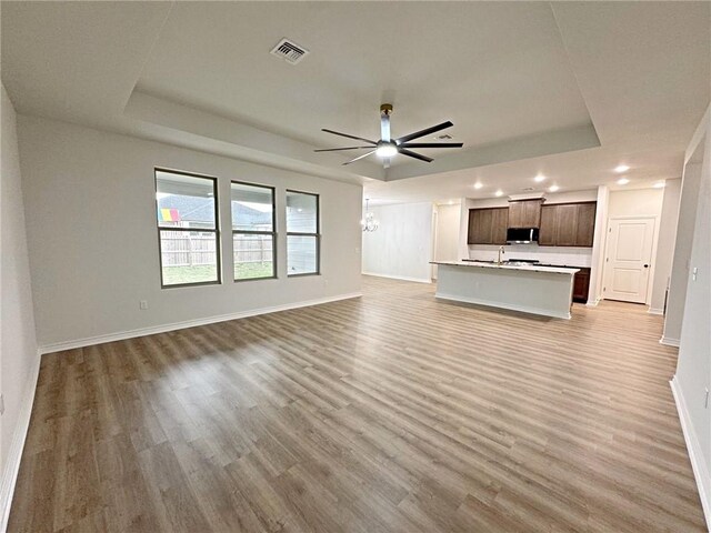 9505 Spanish Oak Dr, Corpus Christi, TX 78410 - unfurnished living room with a raised ceiling, recessed lighting, light wood-type flooring, and baseboards