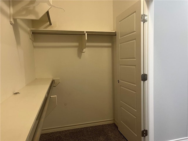 walk in closet featuring dark colored carpet