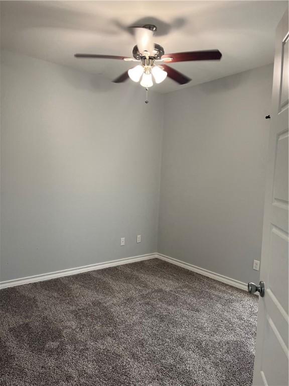 carpeted empty room featuring ceiling fan and baseboards