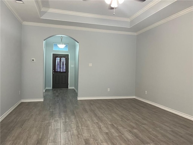 foyer entrance with arched walkways, dark wood-style flooring, a tray ceiling, crown molding, and baseboards