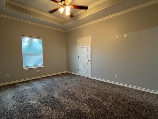 unfurnished room with baseboards, dark carpet, a raised ceiling, and ornamental molding