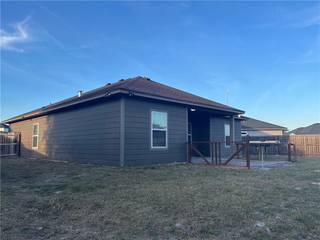 rear view of house with fence, a lawn, and a patio