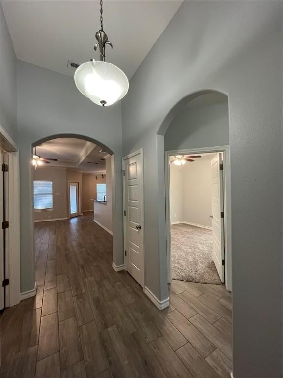 hallway with baseboards, arched walkways, and wood finish floors