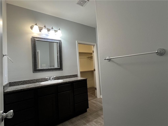 bathroom featuring a spacious closet, visible vents, vanity, and wood finished floors