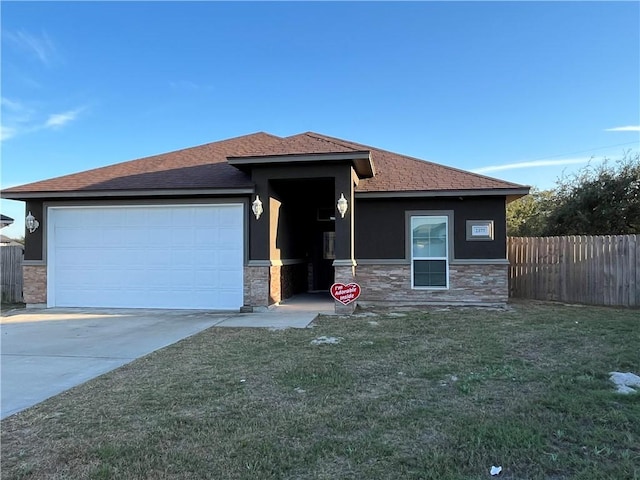 prairie-style house with a garage, stone siding, fence, and a front lawn