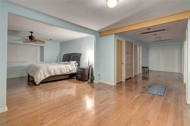 bedroom with ceiling fan, light wood-type flooring, and a textured ceiling