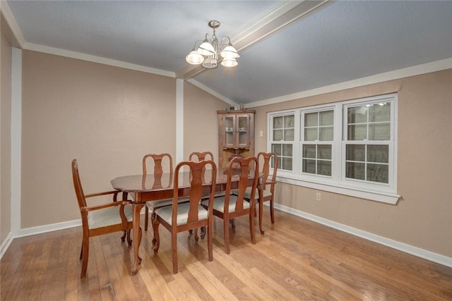 dining room featuring ornamental molding, light wood-type flooring, an inviting chandelier, and lofted ceiling