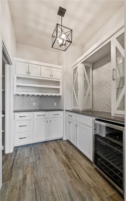 kitchen featuring decorative backsplash, dark countertops, beverage cooler, and dark wood-style flooring