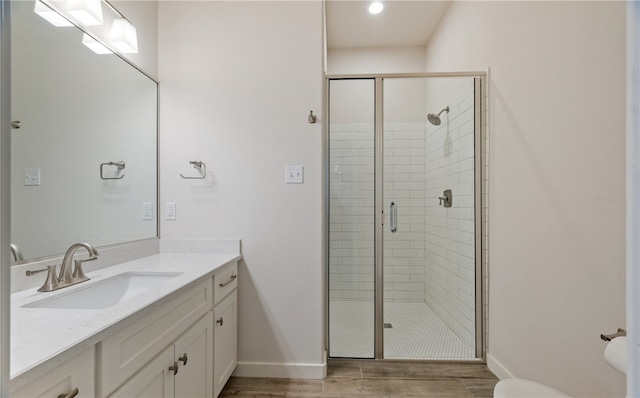 full bathroom with toilet, wood finished floors, a shower stall, baseboards, and vanity