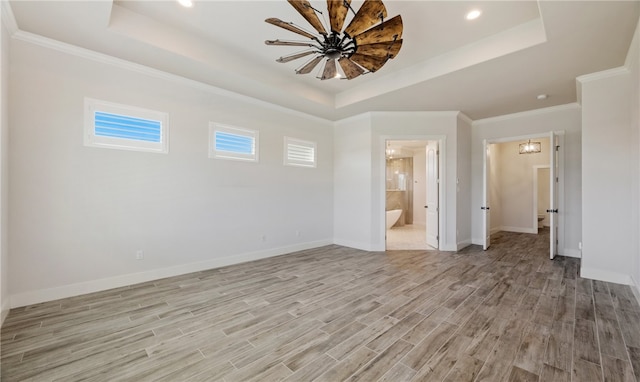 interior space with light wood-style flooring, baseboards, and a tray ceiling