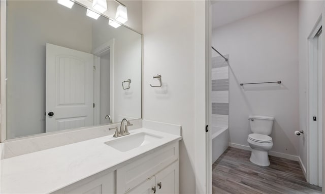 bathroom with toilet, wood finished floors, baseboards, bathing tub / shower combination, and vanity