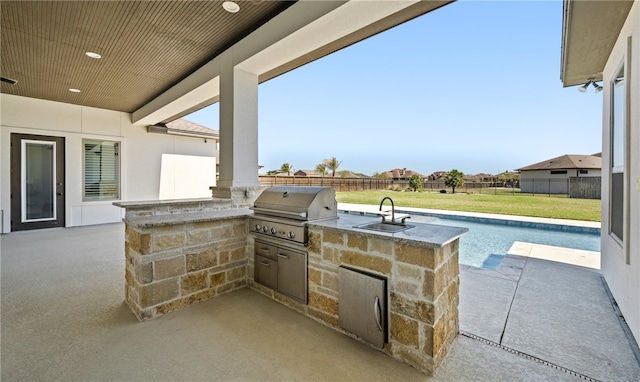 view of patio with grilling area, an outdoor kitchen, a fenced backyard, and a sink