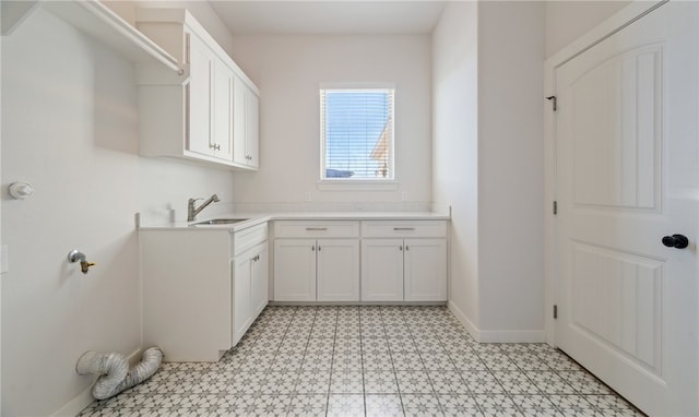 laundry area with a sink, baseboards, and light floors