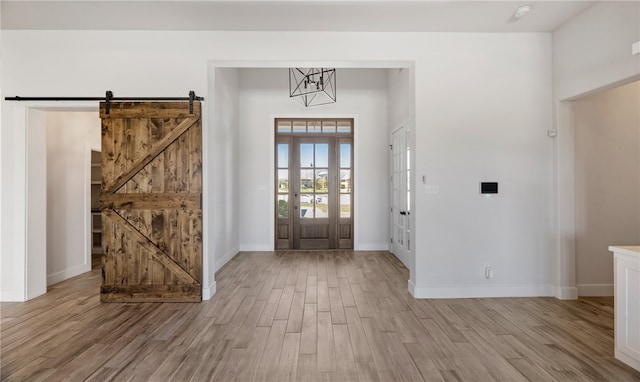 foyer featuring a barn door, light wood-style flooring, and baseboards