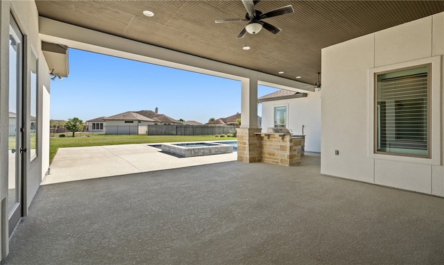 view of patio / terrace featuring fence, a residential view, an outdoor kitchen, an in ground hot tub, and a ceiling fan