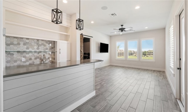 kitchen featuring wood finished floors, a ceiling fan, recessed lighting, a barn door, and backsplash