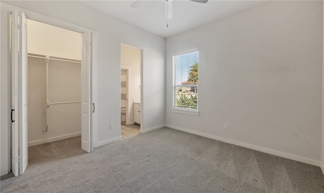 unfurnished bedroom featuring a walk in closet, baseboards, carpet, and a closet