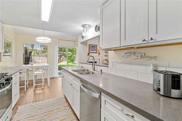 kitchen with light hardwood / wood-style floors, stainless steel appliances, hanging light fixtures, sink, and white cabinetry