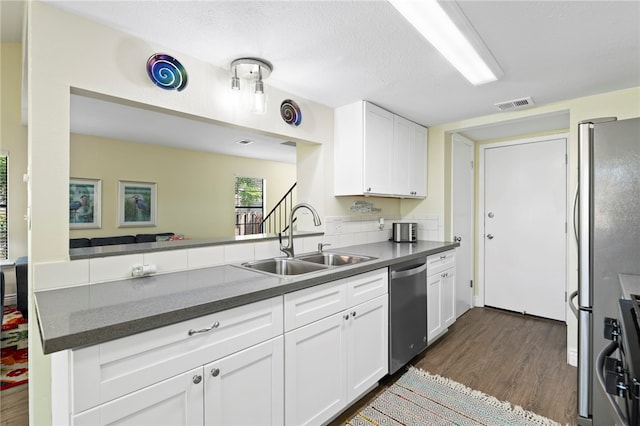 kitchen featuring dark wood-type flooring, white cabinets, kitchen peninsula, sink, and appliances with stainless steel finishes