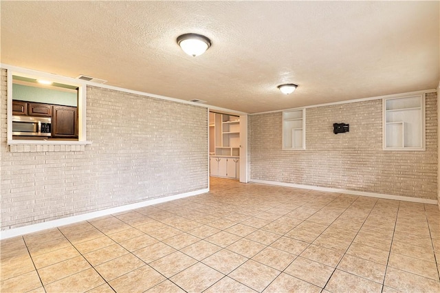 5905 Norvel Dr, Corpus Christi, TX 78412 - unfurnished room with brick wall, a textured ceiling, and light tile patterned floors