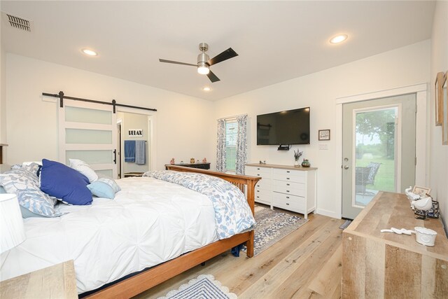 bedroom with access to outside, light wood-type flooring, a barn door, multiple windows, and ceiling fan