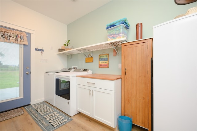 clothes washing area with light wood-type flooring, cabinets, and washing machine and clothes dryer