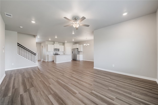 unfurnished living room with hardwood / wood-style floors and ceiling fan with notable chandelier