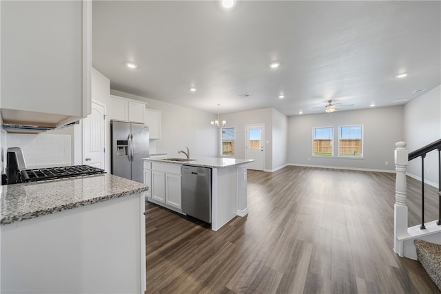 kitchen featuring appliances with stainless steel finishes, dark hardwood / wood-style flooring, ceiling fan with notable chandelier, white cabinetry, and an island with sink