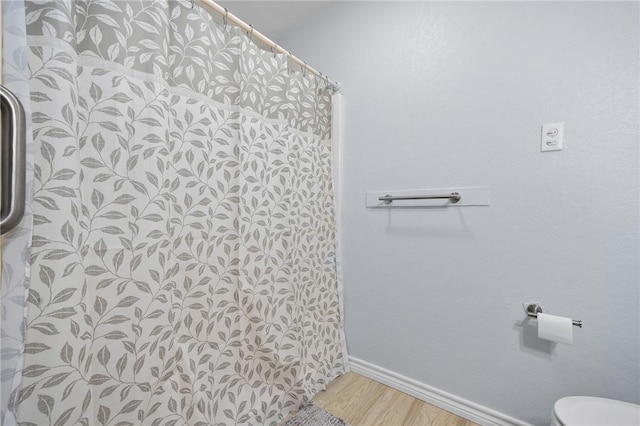 1003 S Pearl St, Rockport, TX 78382 - bathroom with wood finished floors, toilet, baseboards, and curtained shower